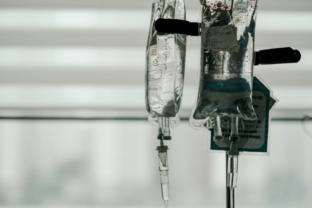 A close-up of medical IV fluid bags hanging in a hospital, representing health emergencies while travelling.